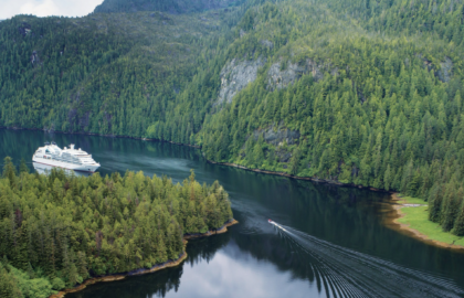 Photo from Seabourn Quest of their Alaskan Cruise. Cruise ship in dark blue waters surrounded by green mountains in Alaska.